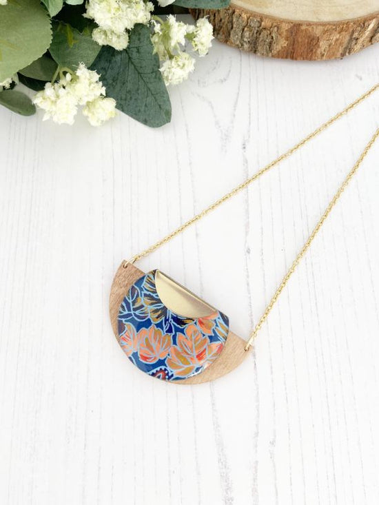 Tropical Leaf Handmade Wooden Necklace, made with FSC birch and hand screened paper with a leaf design in shades of blue, red and peach, finished with gold necklace