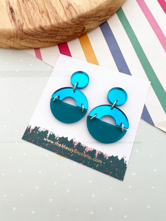 Blue earrings on a display card with a colorful striped background