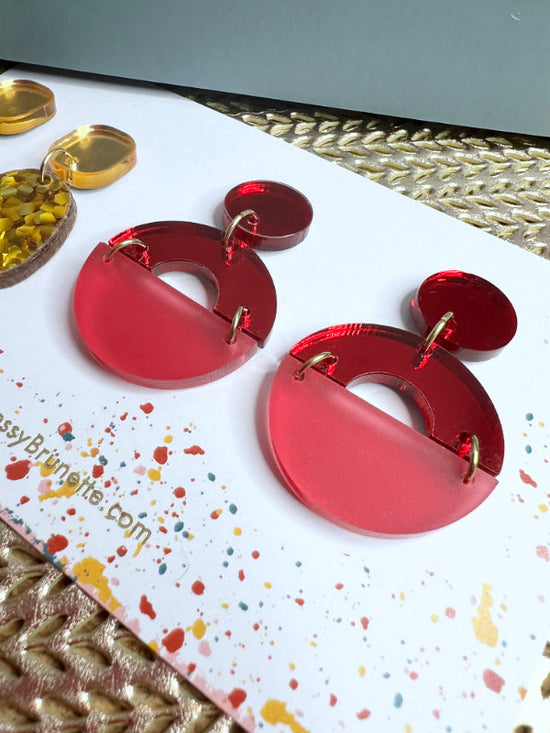 Red earrings on a colorful card with text