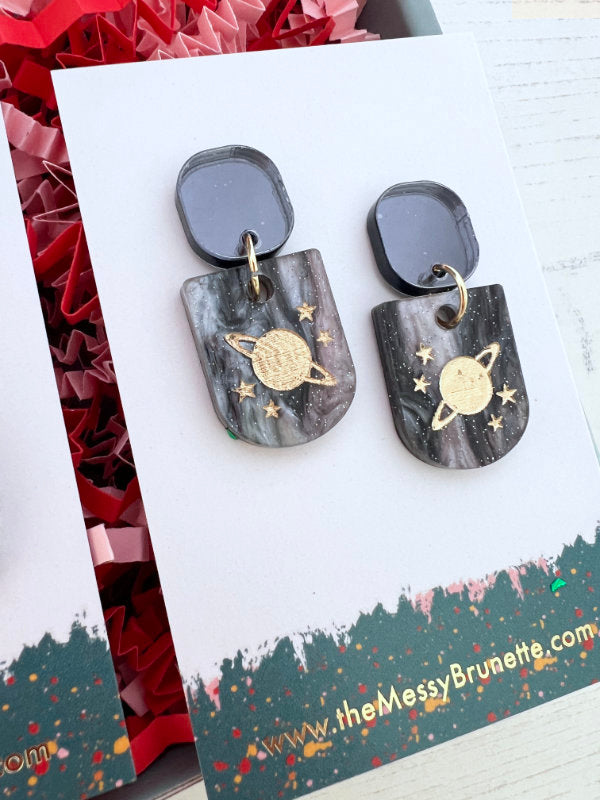 Pair of earrings with space-themed design on a branded card
