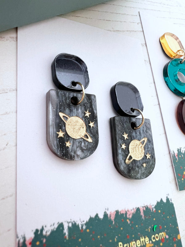 Pair of earrings with space-themed designs on a white surface