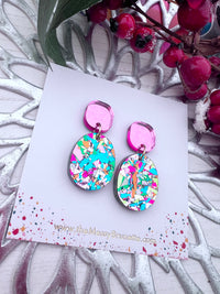 Multi colour gllitter shard earrings on a branded card with decorative background