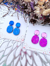 Glitter Blue and pink earrings on decorative cards with dried flowers in the background