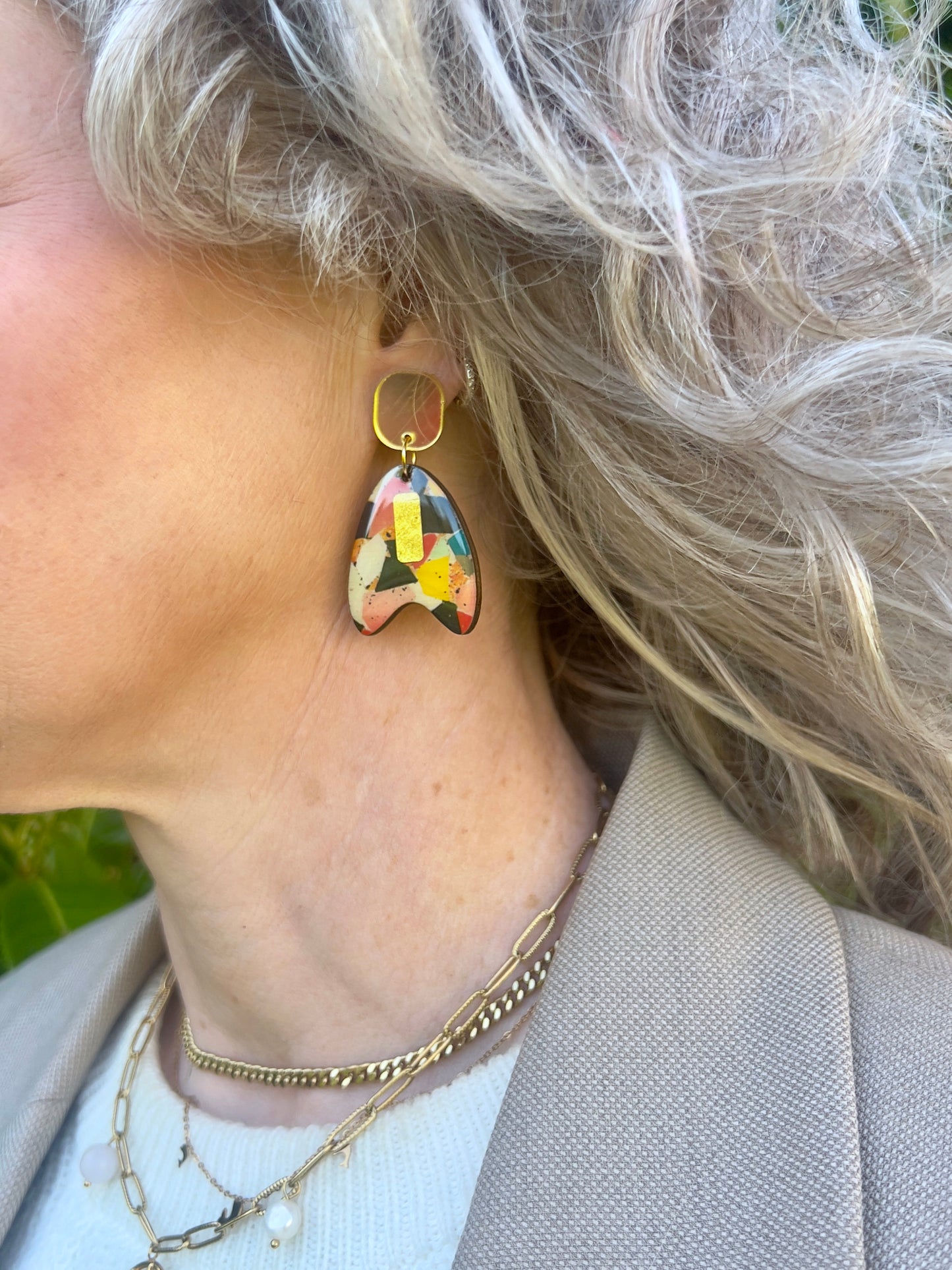 Close-up of a person wearing mosaic style of  earrings with a neutral background