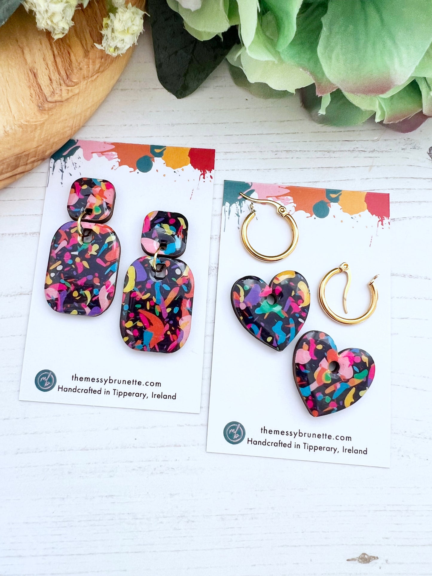 Colourful earrings in 2 styles, bar shape and hearts on branded cards with a white background