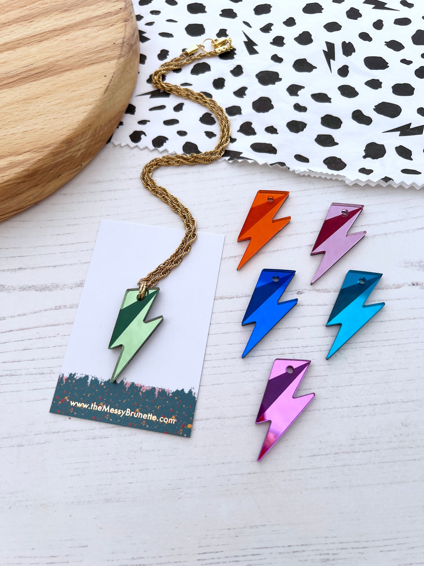 Colorful lightning bolt necklaces on a white surface with a branded card.