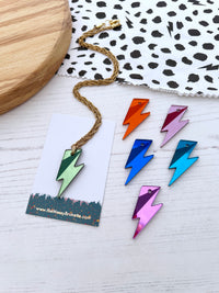Colorful lightning bolt necklaces on a white surface with a branded card.