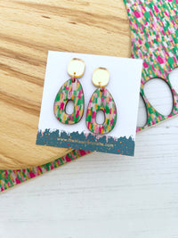 Colourful brush stroke pink and green earrings on a white card with a patterned background