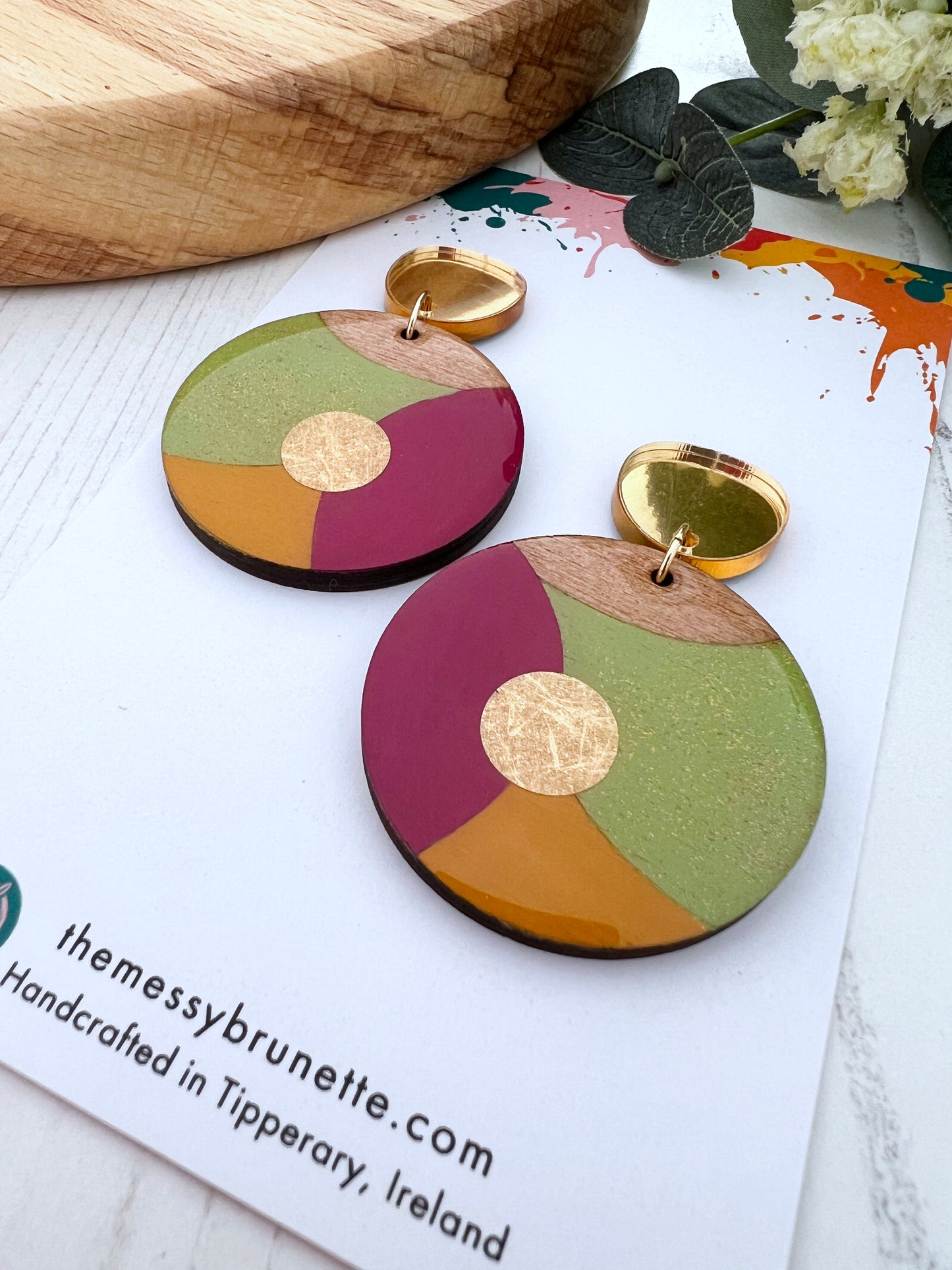 Colourful circular earrings with gold accents on a white surface with 'themessybrunette' branding.