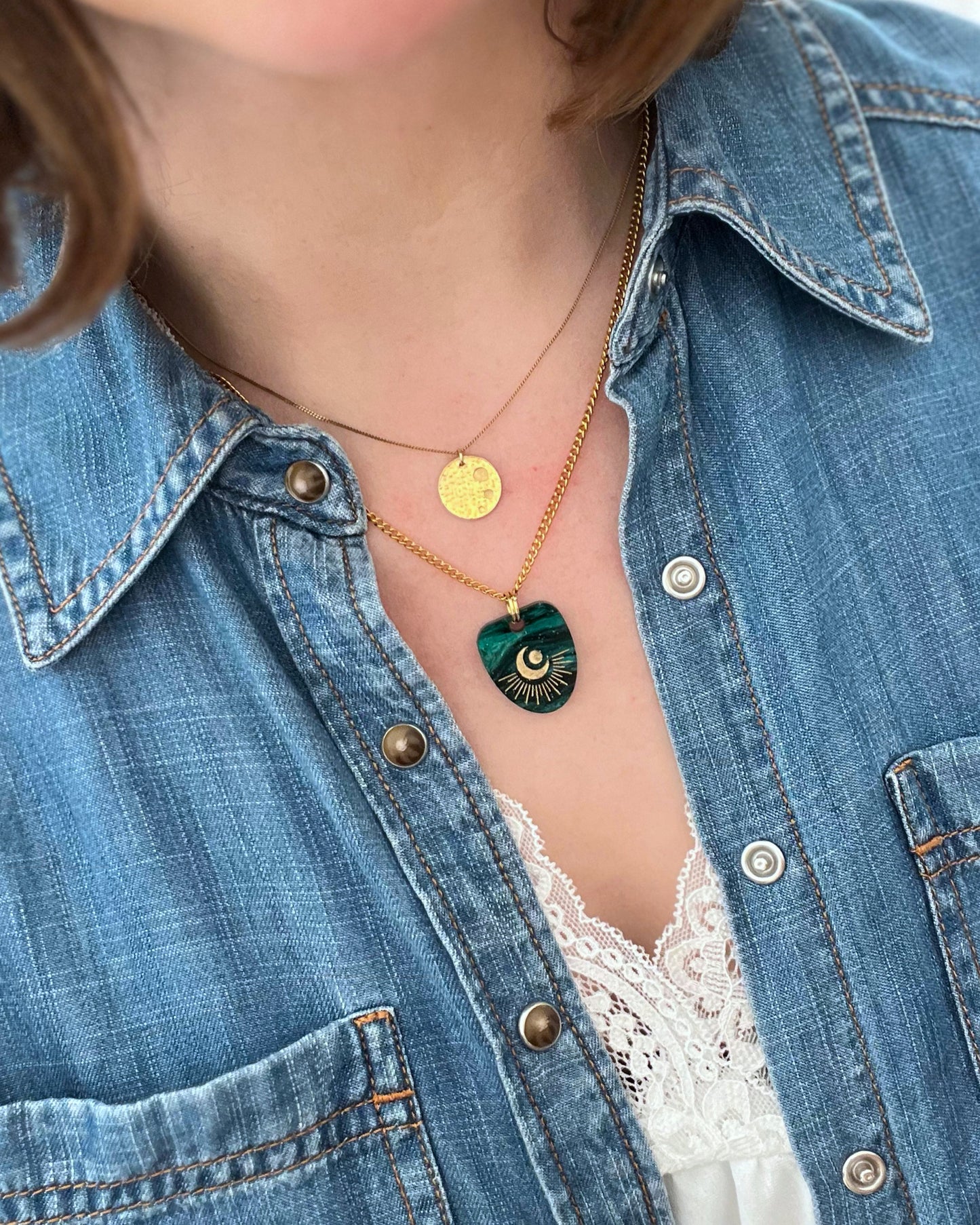 Person wearing a denim jacket and a celestial necklace pendant 