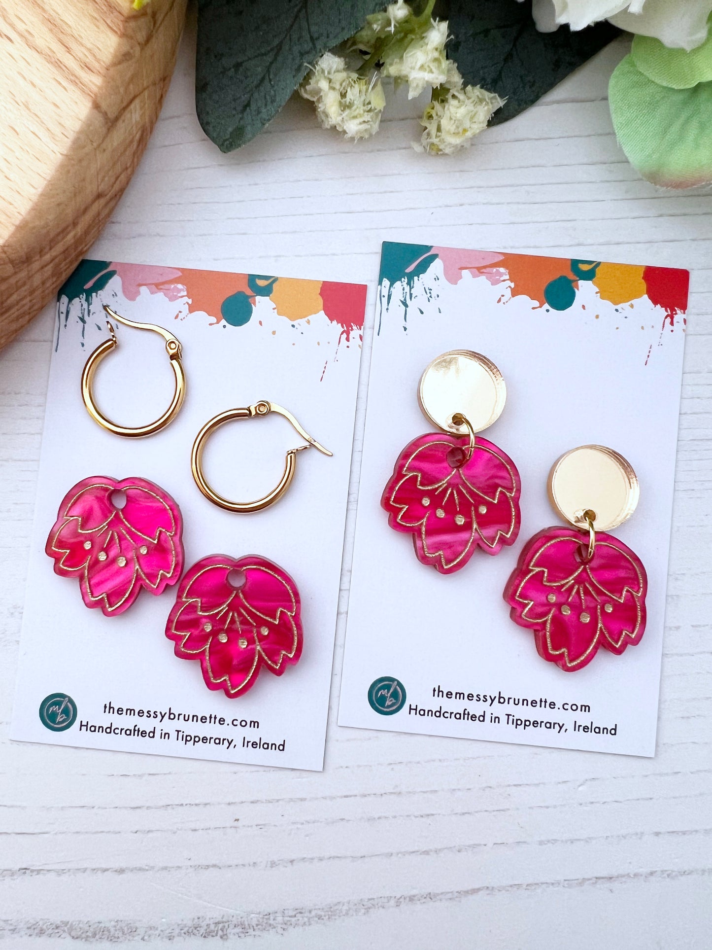 Pair of pink floral cherry blossom earrings on a branded card with a white background
