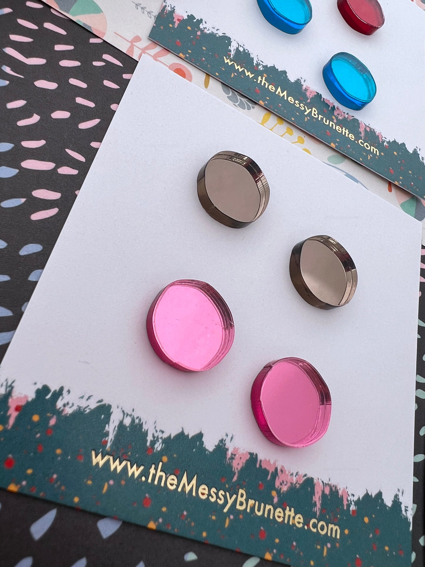 Colourful acrylic stud earrings on a branded card with 'The Messy Brunette' website.