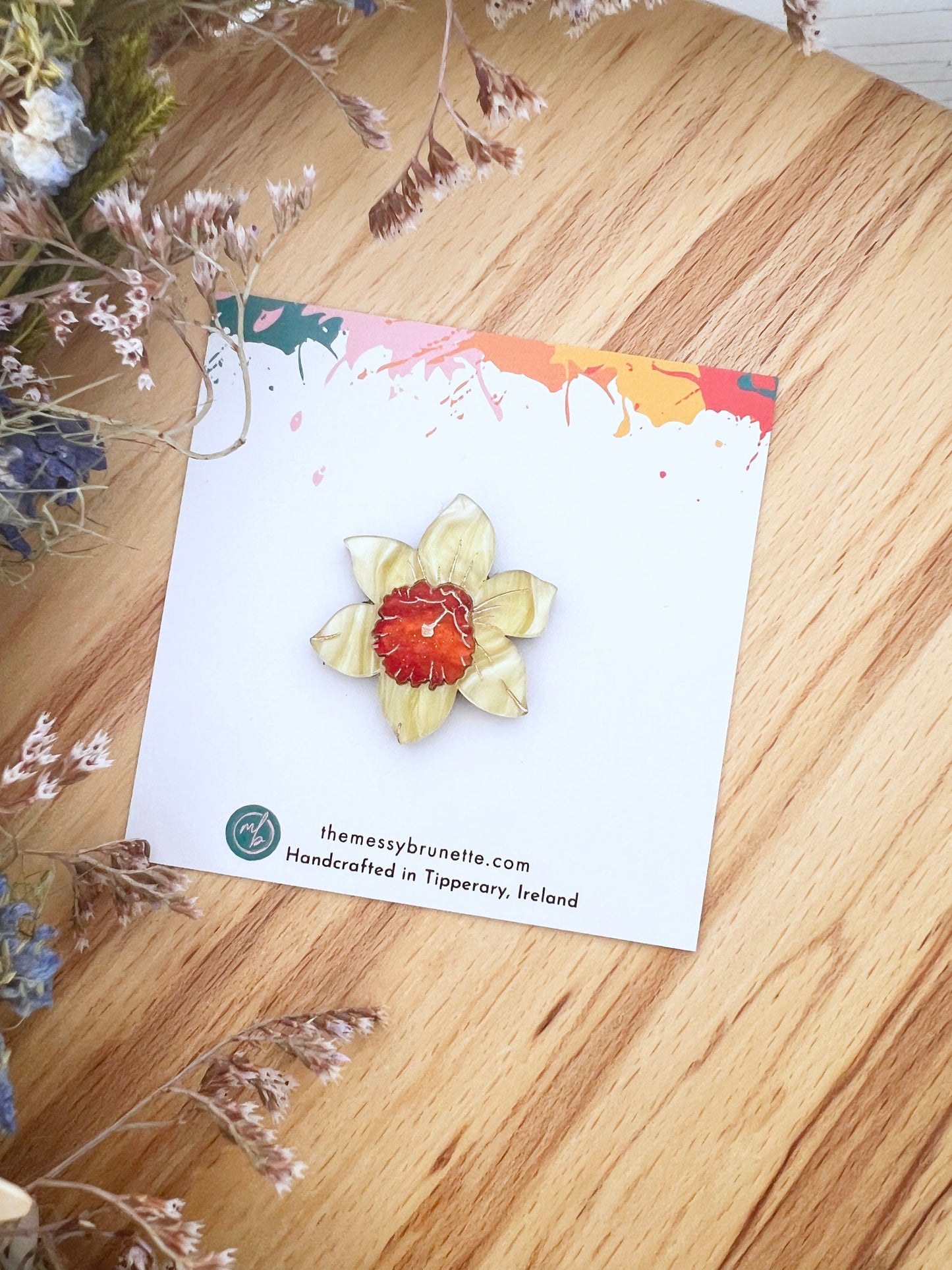 daffodill broooch pin on a wooden surface