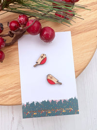 Robin stud earring on a branded card with red berries and greenery in the background