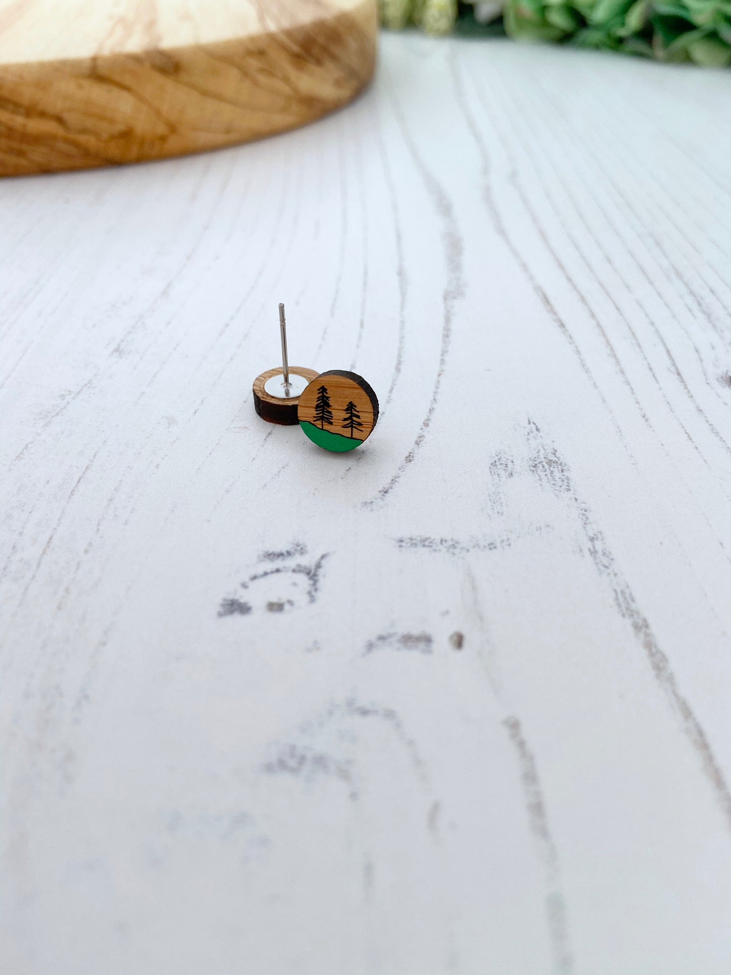 Wooden stud earrings with nature-themed design on a marble surface