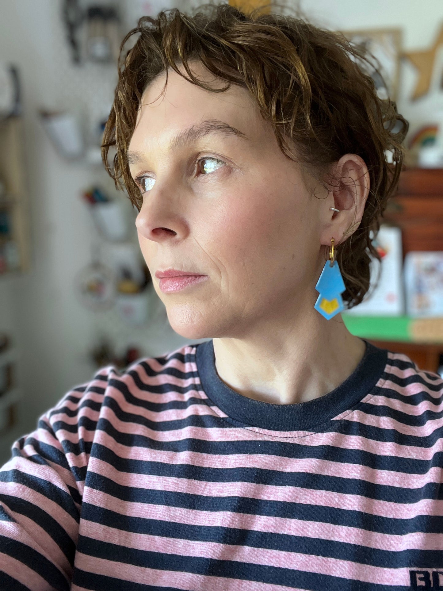 Person wearing blue hoop earrings indoors