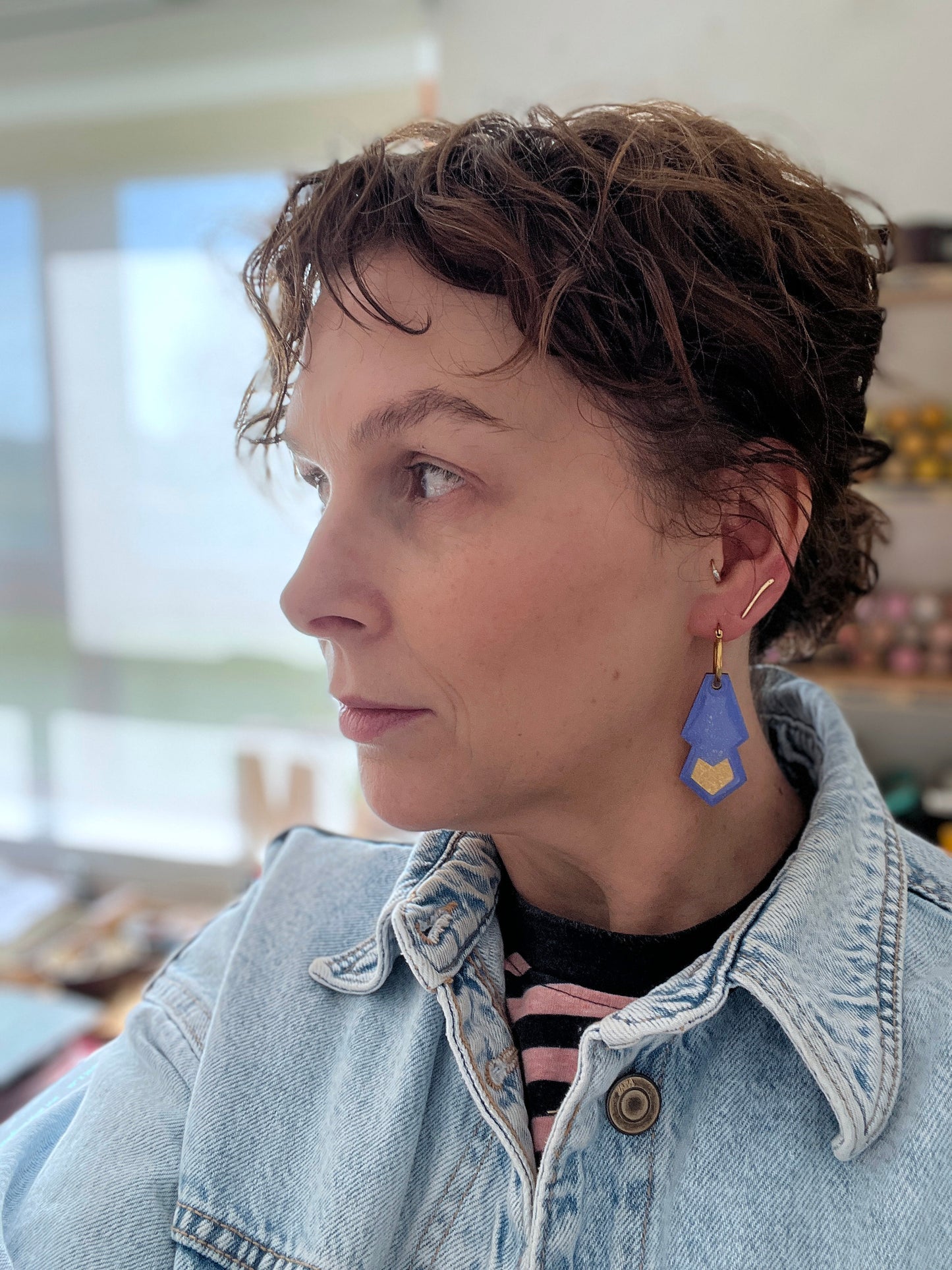 Woman wearing a denim jacket and colou rful hoop earrings indoors