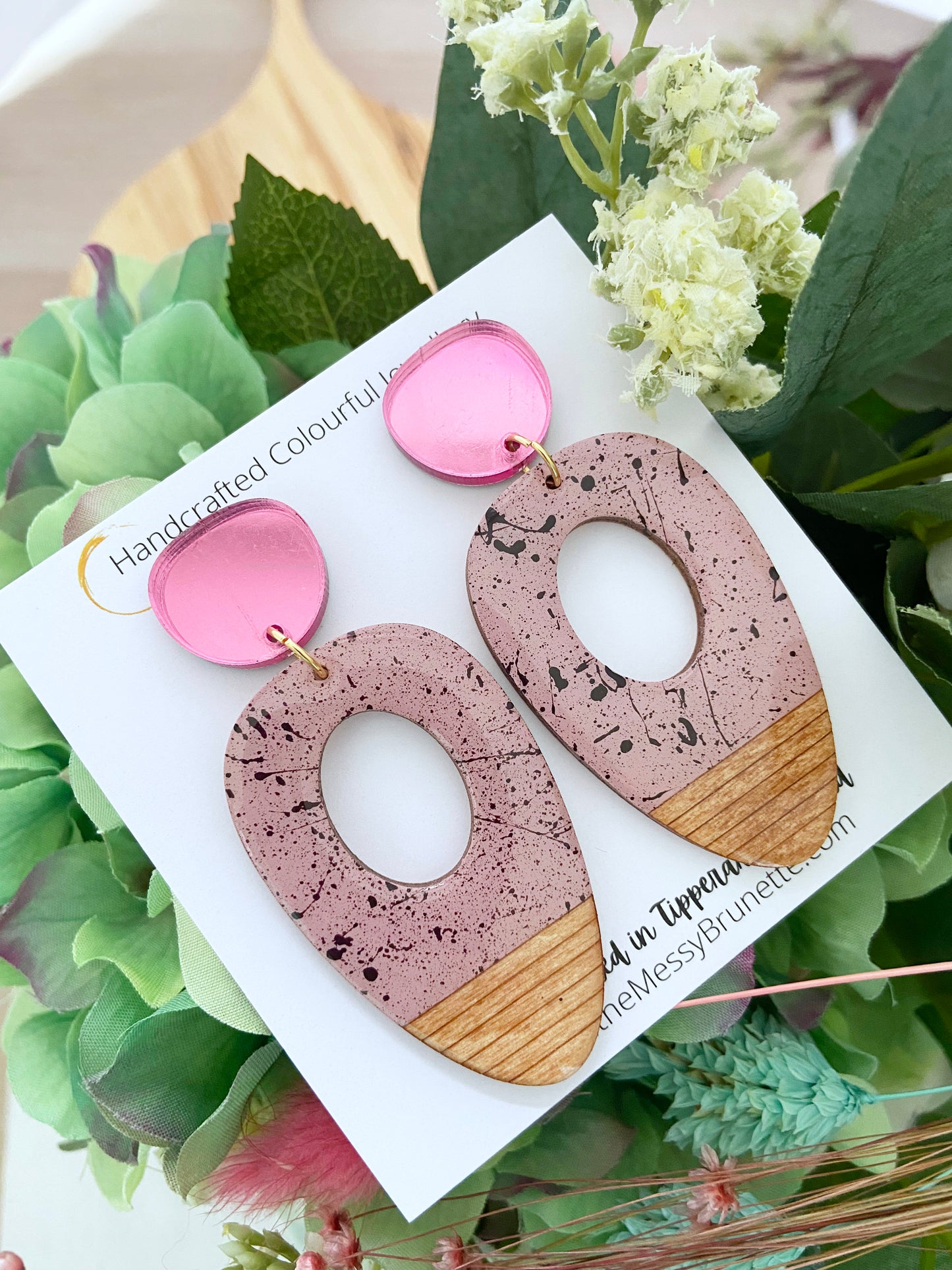 Speckled pink big oval wood earring drops on a card with greenery in the background