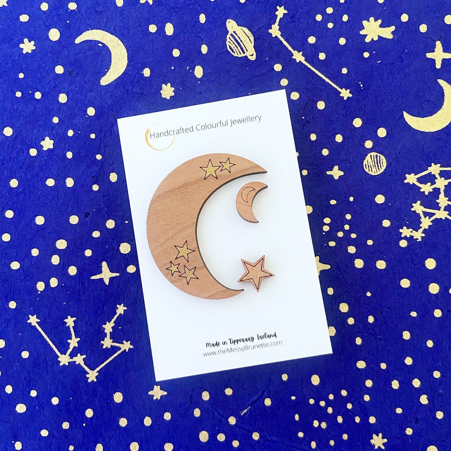 Wooden moon and star earrings on a card with a celestial pattern background