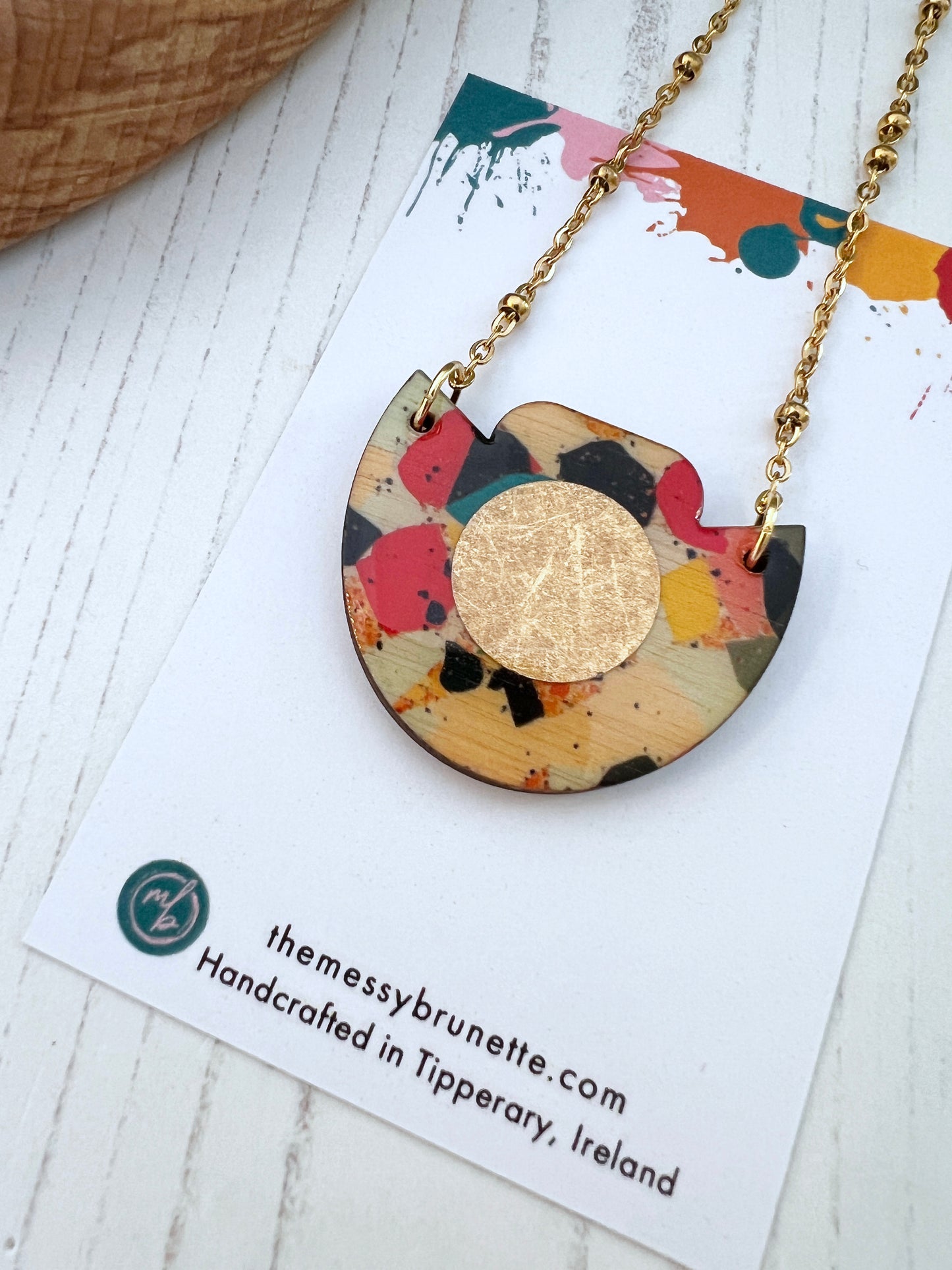 Mosaic tile necklace with gold disc on white background