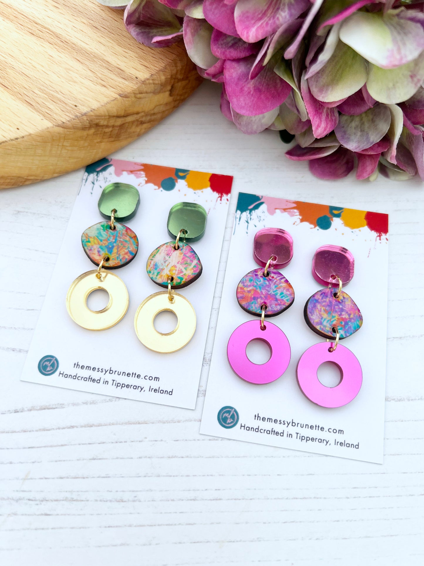 Colourful earrings on cards with hydrangeas in the background
