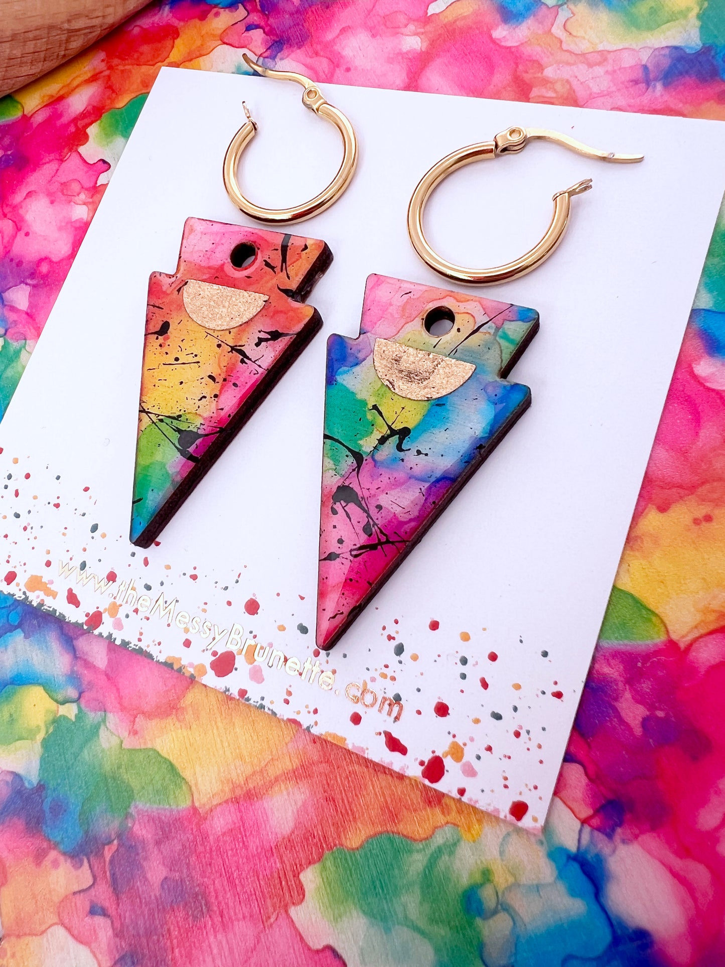 Colourful abstract triangle earrings on a colorful watercolor background