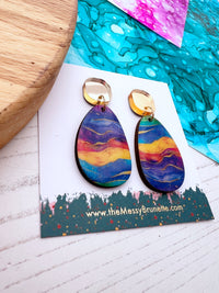 Multi coloured wood earrings on a branded card with a colourful background