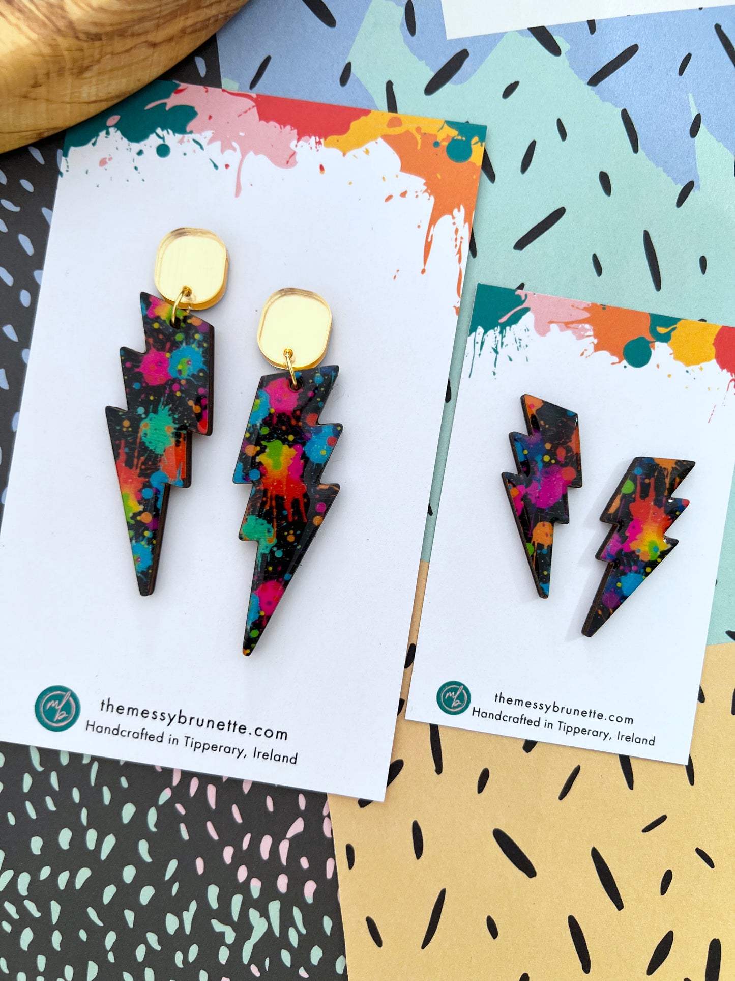 Colourful lightning bolt earrings on branded cards with a colourful background