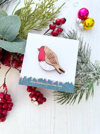Bird-shaped brooch on a card with Christmas decorations