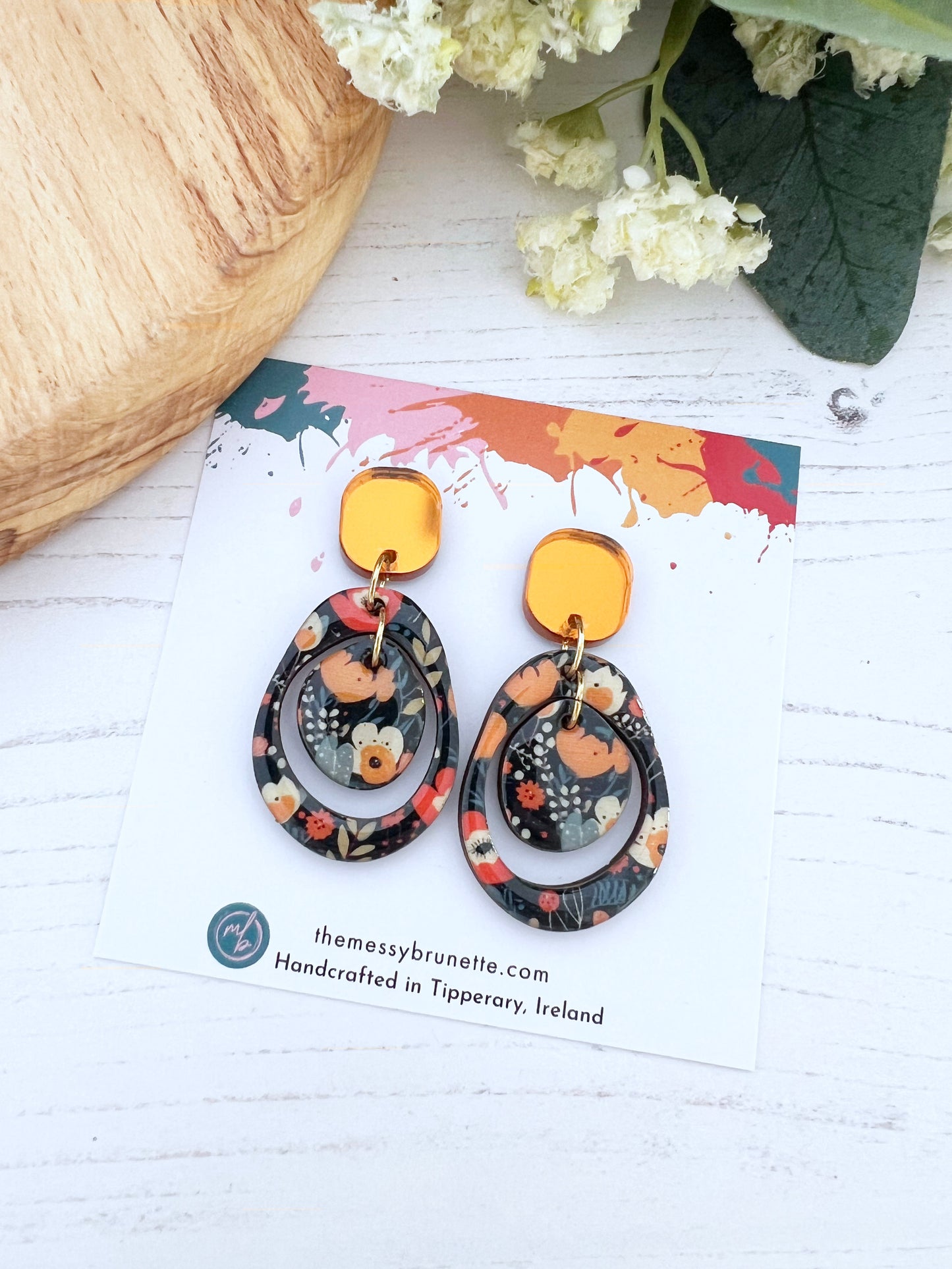 Pair of floral earrings on a branded card with a white background
