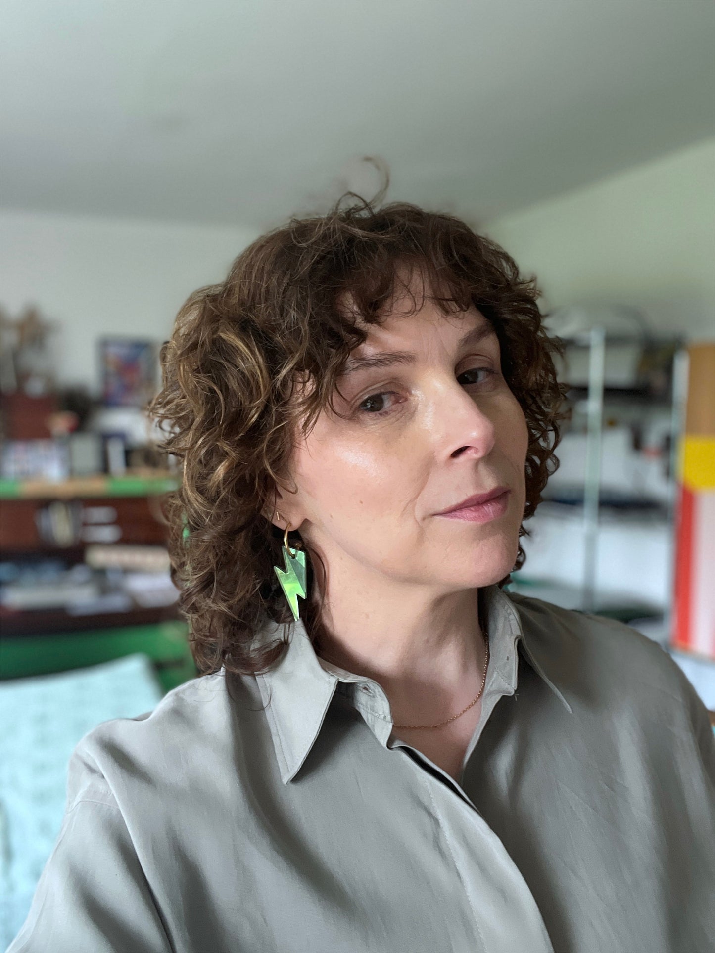 Woman with curly hair wearing green bolt hoops earring 