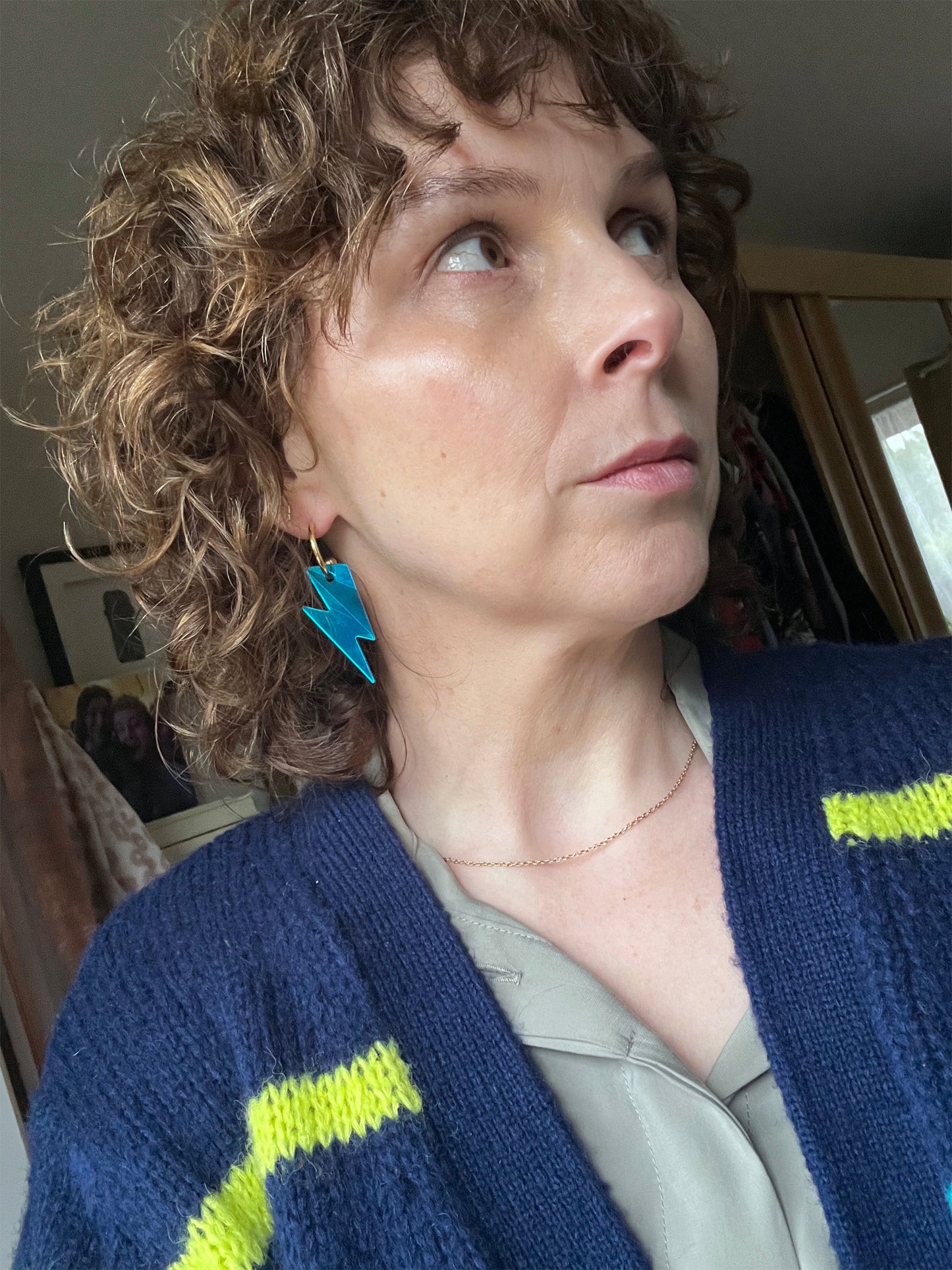 Woman wearing turquoise bolt hoops earrings  looking upwards.