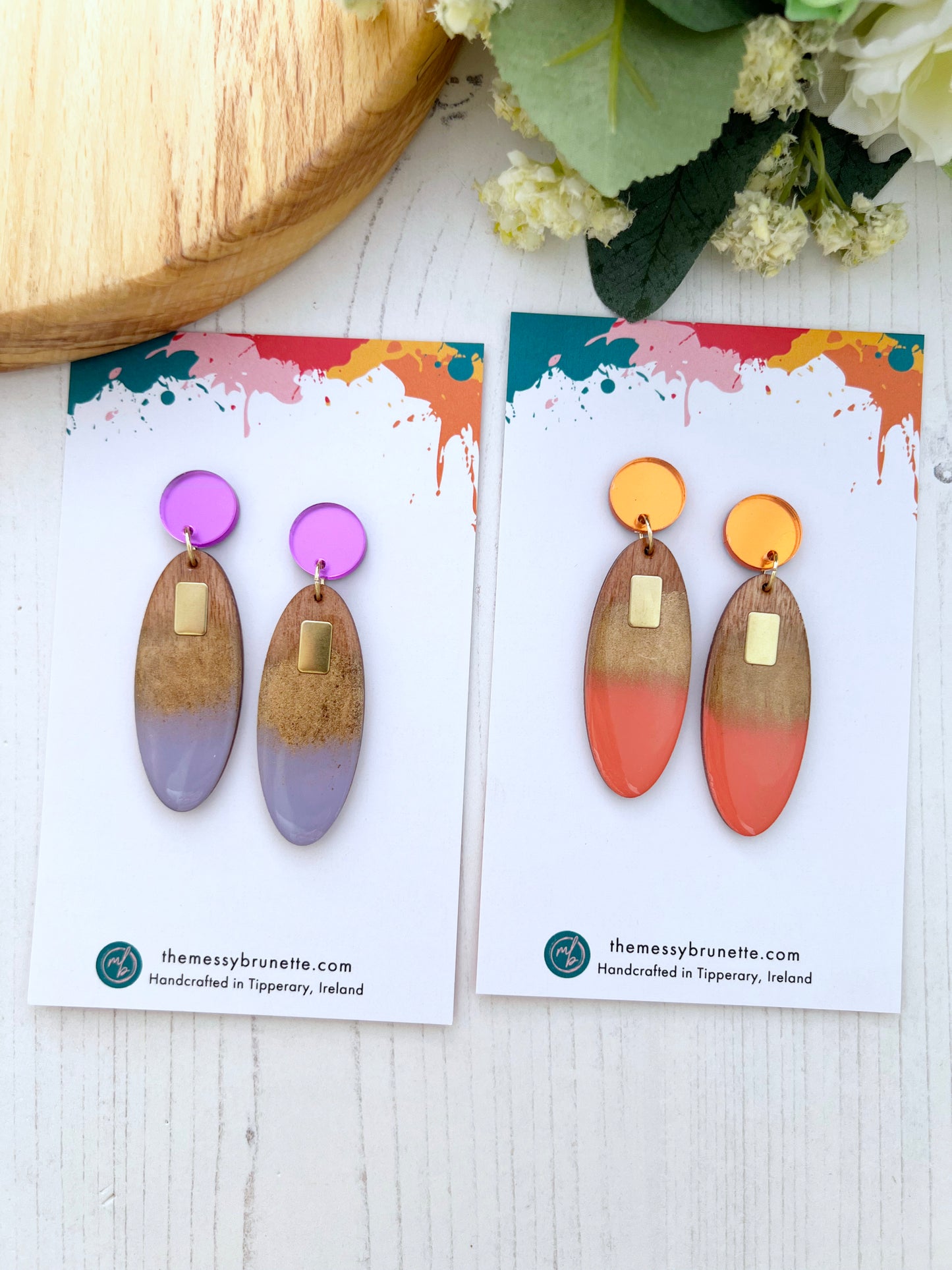 Pair of colourful earrings on branded card with floral background