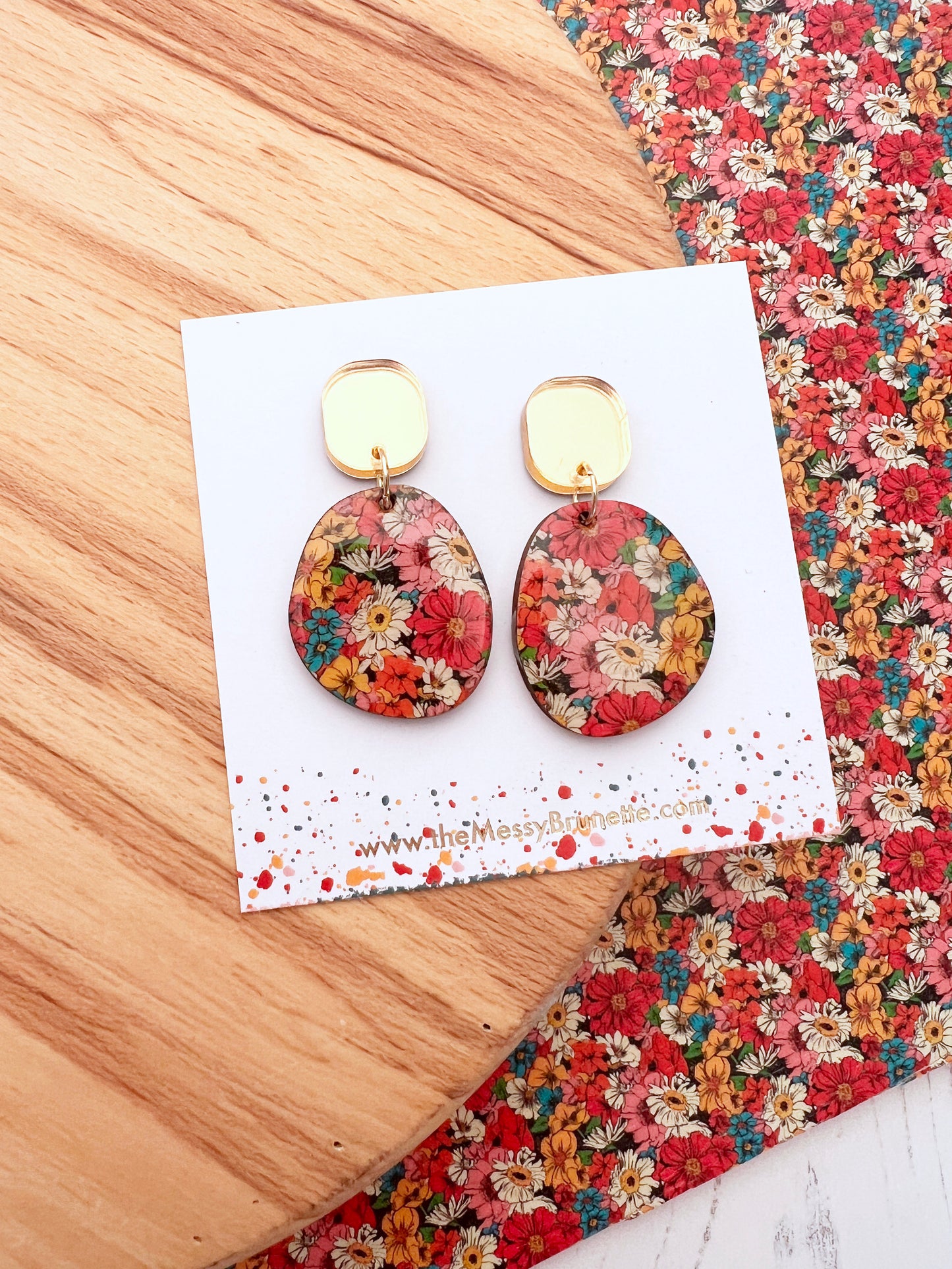 Floral earrings on a branded card with a floral background