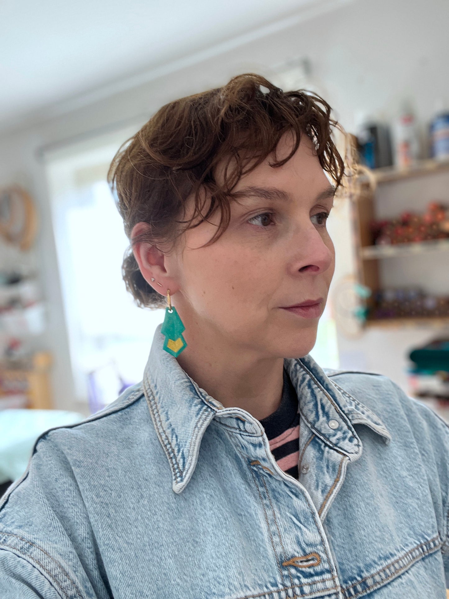 Woman wearing a denim jacket and green hoop earrings