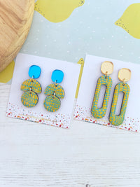 Pair of blue and yellow earrings on a white card with a yellow and blue background