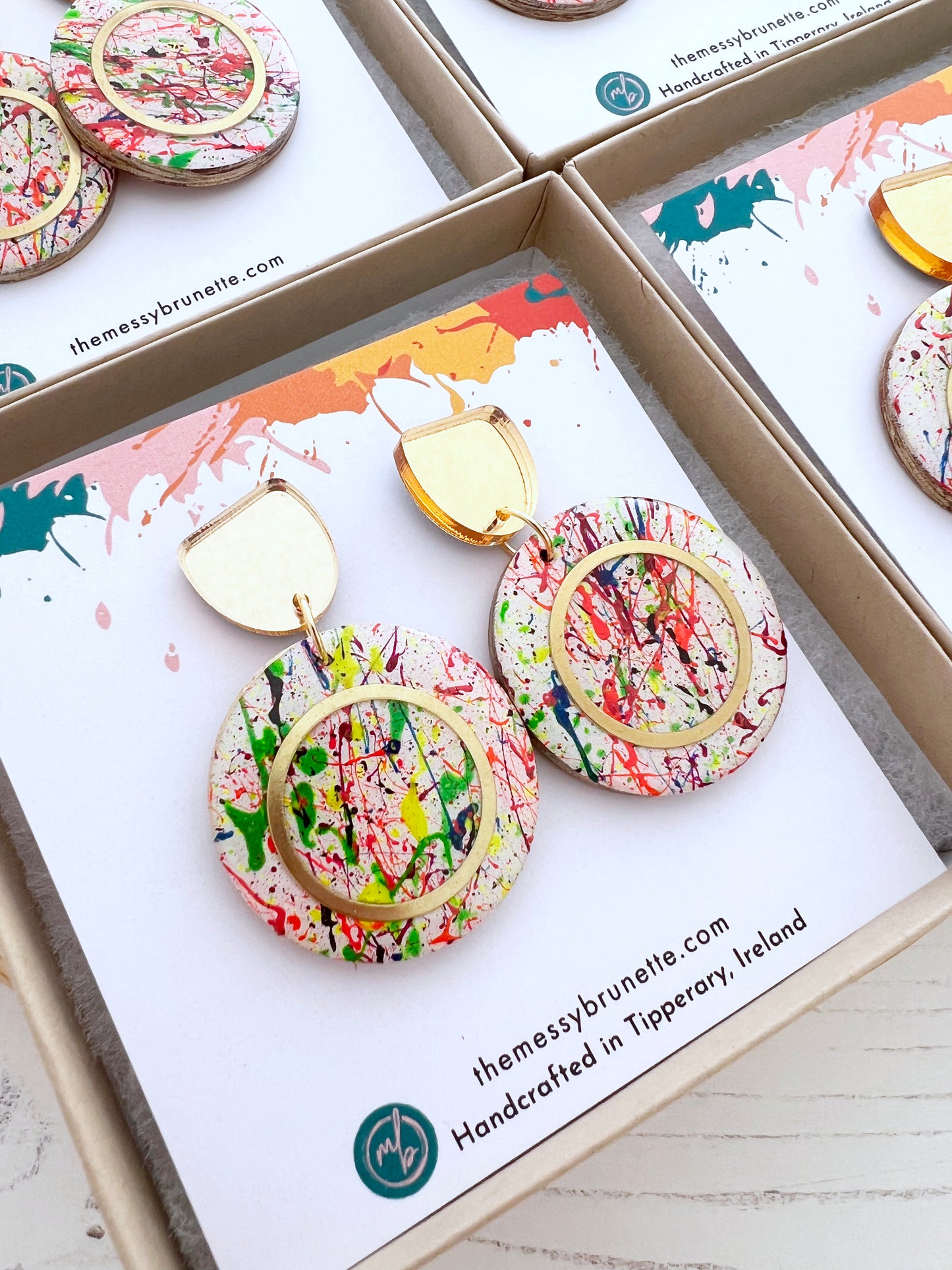 Multi colour paint splatter earrings displayed on a branded card with 'themessybrunette' branding.