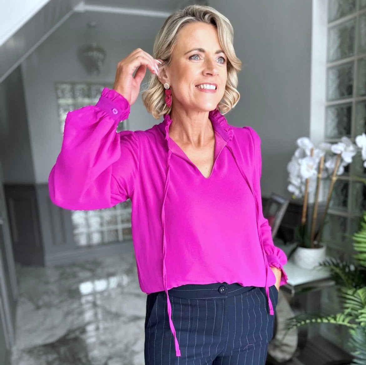 Woman wearing a bright pink blouse with heart shaped painted wood earrings