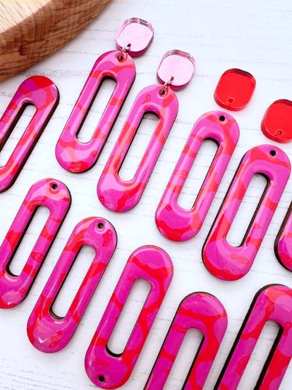 Pink and red patterned earrings on a white surface