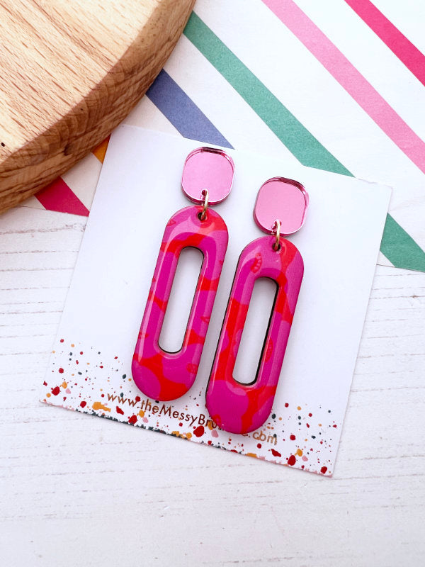 Pink and red abstract earrings on a colorful card with 'The Messy Box' branding.