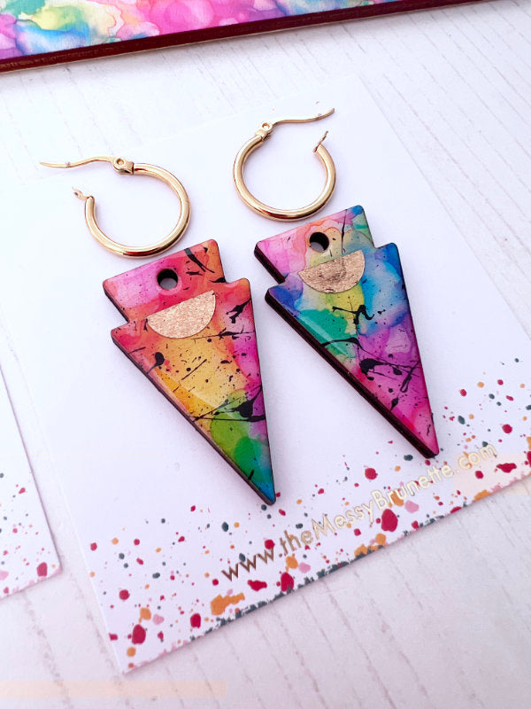 Colorful abstract-patterned earrings on a colorful background with hoops