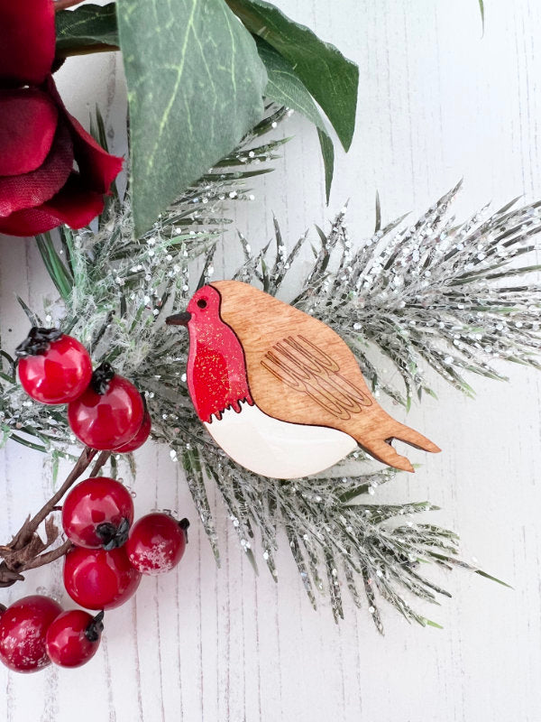 Wooden robin handpainted brooch on a branch with red berries and green leaves.