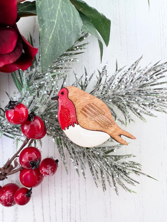 Wooden robin handpainted brooch on a branch with red berries and green leaves.