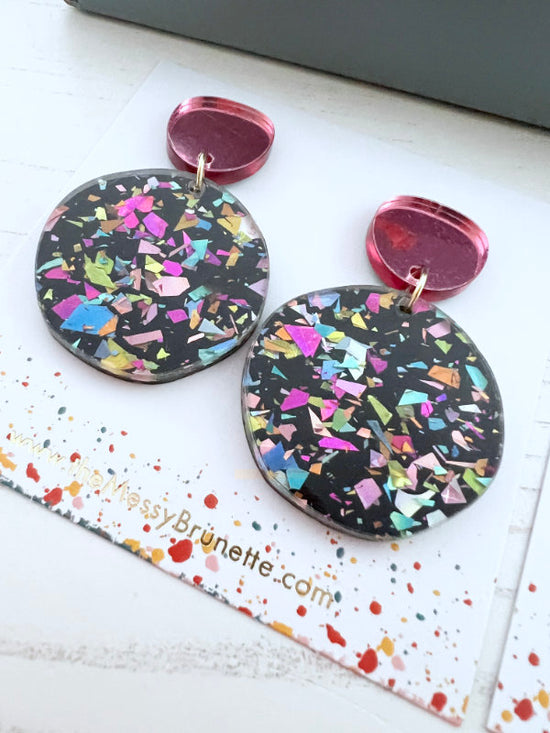 Colorful round earrings on a branded card with a white background