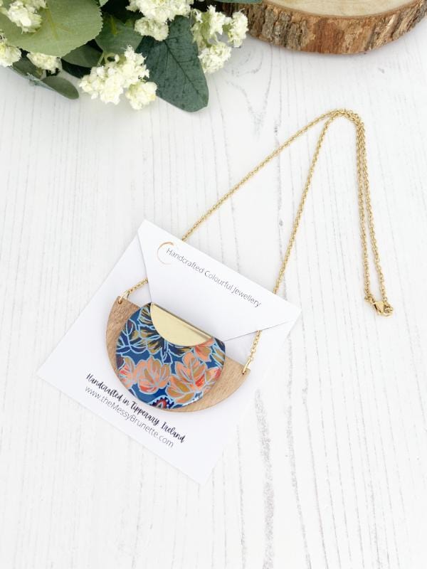 Load image into Gallery viewer, Tropical Leaf Handmade Wooden Necklace, made with FSC birch and hand screened paper with a leaf design in shades of blue, red and peach, finished with gold necklace
